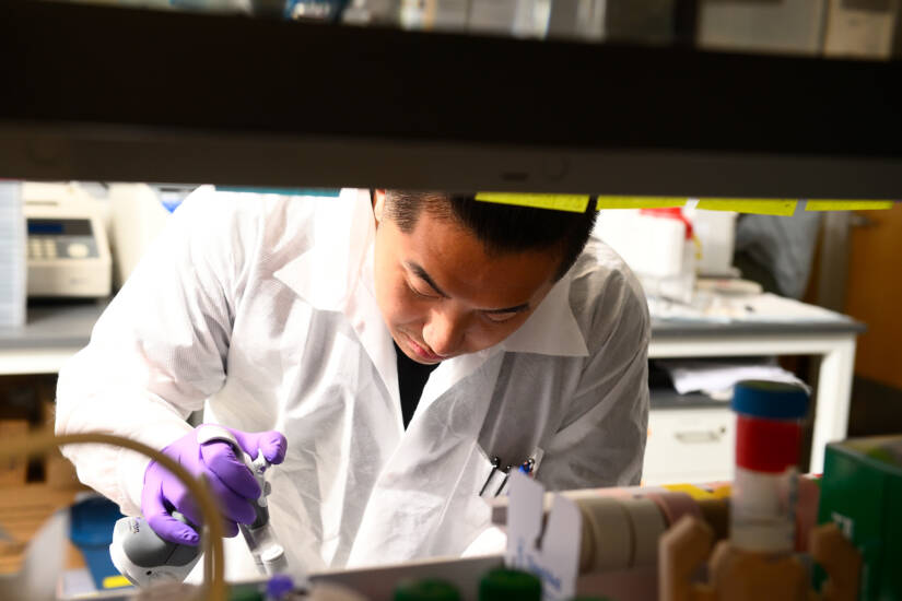 A researcher wearing a white lab coat working in a science lab